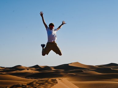 Kind voller Freude beim Springen auf den weichen Sanddünen der Sahara – Marokko mit Kindern