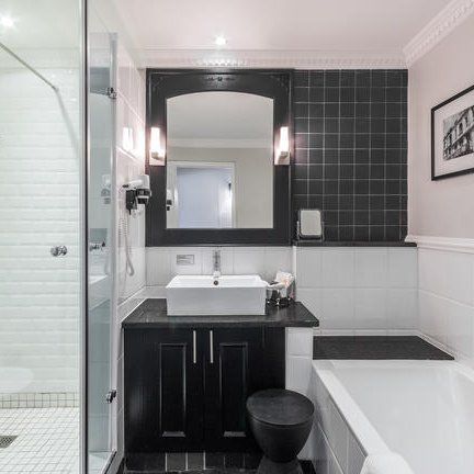 Ein modernes Badezimmer mit einer eleganten Dusche, einer Badewanne und einem stilvollen Waschbecken aus schwarzem Marmor.