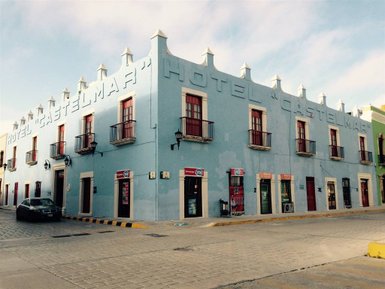 Das Hotel Castelmar ist ein blaues Gebäude mit roten Fensterläden und einem charmanten, historischen Stil.
