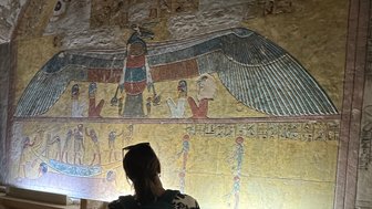Frau bestaunt die antiken Wandmalereien im Tal der Könige in Luxor – Ägypten Reise mit Kindern