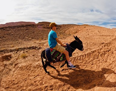 Junge genießt eine spannende Esel-Tour durch die historischen Landschaften von Aït Ben Haddou – Familienurlaub in Marokko