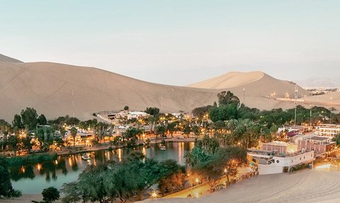Eine malerische Oase umgeben von sanften Sanddünen, beleuchtet von warmen Lichtern, die eine friedliche Atmosphäre schaffen.
