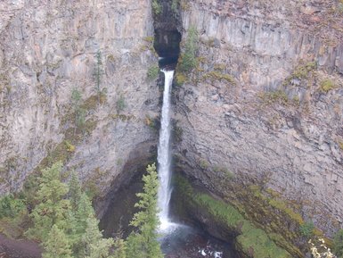 Ein majestätischer Wasserfall stürzt in eine tiefe Schlucht, umgeben von üppigen, grünen Bäumen und steilen Felswänden.