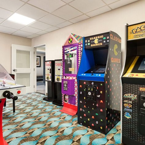 Ein Spielbereich mit verschiedenen Arcade-Automaten, darunter Pac-Man und klassische Spiele, in einem modernen Raum.