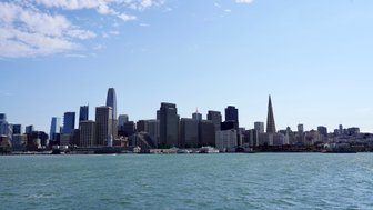 Die Skyline von San Francisco zeigt moderne Wolkenkratzer und den ikonischen Transamerica-Pyramid, umgeben von Wasser.