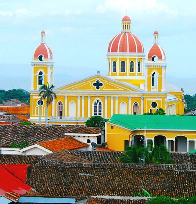 Die leuchtend gelbe Kathedrale mit roten Kuppeln erhebt sich über die bunten Dächer von Granada, Nicaragua.