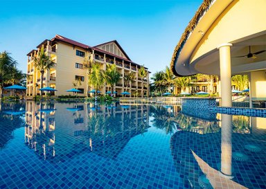 Ein luxuriöser Pool spiegelt die Farben des Himmels wider, umgeben von Palmen und einem eleganten Resortgebäude.
