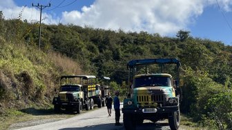 Zwei bunte Jeeps stehen auf einer unbefestigten Straße, umgeben von üppigem Grün und einem strahlend blauen Himmel.