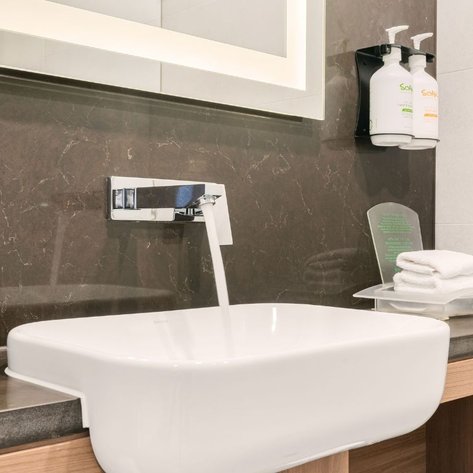 Ein moderner Waschbeckenbereich mit einem eleganten weißen Becken und einem glänzenden Wasserhahn, der laufendes Wasser zeigt.