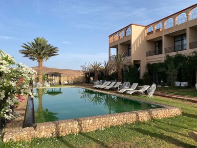 Ein klarer Pool spiegelt den Himmel und die umgebenden Palmen wider, während lounge-Bereiche einladend wirken.