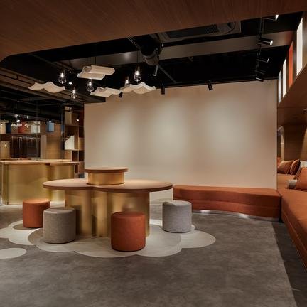 Ein modernes, stilvolles Interieur mit runden Tischen und bequemen Sitzgelegenheiten in warmen Farbtönen.