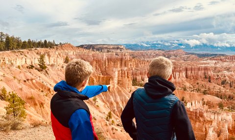 Zwei Jungen stehen am Rand des Bryce Canyon und betrachten die beeindruckenden Felsformationen in der Ferne.