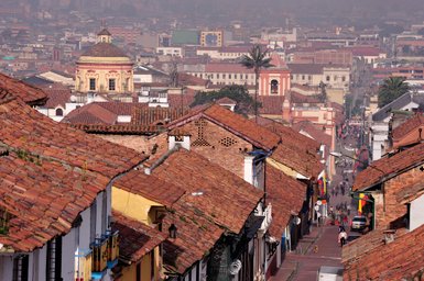 Blick auf die bunten Dächer der Candelaria in Bogotá, mit historischen Gebäuden und einer lebhaften Straße im Hintergrund.