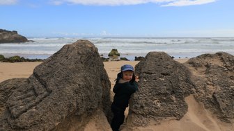 Kleines Kind erkundet zwischen Felsen den Brenton Beach – Garden Route mit Kindern