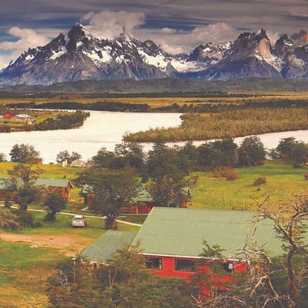 Eine malerische Landschaft mit Bergen im Hintergrund, einem Fluss und mehreren roten und grünen Hütten in der Nähe.