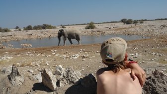 Ein Junge beobachtet gespannt einen Elefant am Wasserloch - Namibia mit Jugendlichen