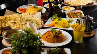 Ein reichhaltiges Buffet mit verschiedenen Gerichten, darunter Reis, Naan, Gemüse und Getränke, die zum Essen einladen.