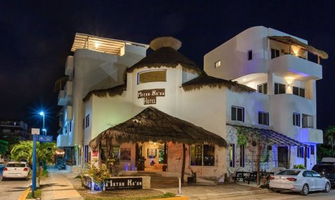 Das Matan K'aan Hotel präsentiert sich mit einem einladenden Eingangsbereich und einem strohgedeckten Dach in der Nacht.