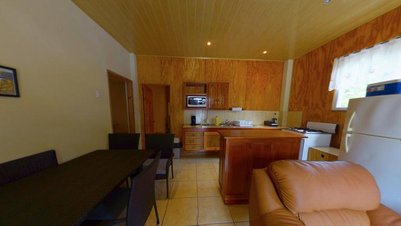 Eine moderne Küche mit Holzverkleidung, ausgestattet mit einem Kühlschrank, Herd und Mikrowelle, strahlt Gemütlichkeit aus.