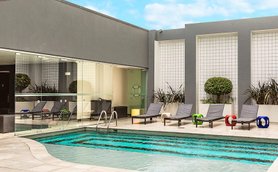 Ein moderner Poolbereich mit Liegen und bunten Schwimmreifen, umgeben von stilvollem, minimalistischem Design.