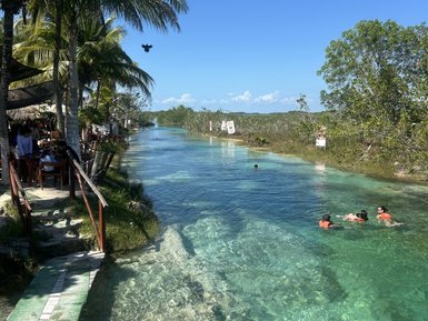 Ein klarer Wasserlauf umgeben von Palmen, in dem Menschen mit Schwimmwesten fröhlich schwimmen und sich entspannen.