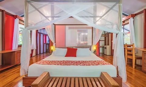 Ein stilvolles Schlafzimmer mit einem großen Bett, umgeben von hellen Wänden und Holzfußboden, strahlt Ruhe und Eleganz aus.