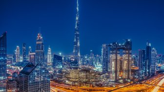 Die beeindruckende Skyline von Dubai erstrahlt nachts in bunten Lichtern, mit dem Burj Khalifa als markantem Mittelpunkt.
