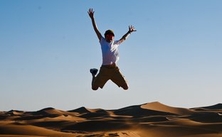Kind voller Freude beim Springen auf den weichen Sanddünen der Sahara – Marokko mit Kindern