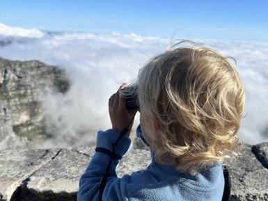 Junge schaut mit Fernglas über die Landschaft vom Tafelberg – Südafrika mit Kindern