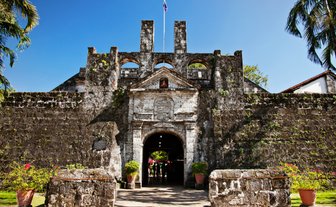 Die beeindruckende Fassade von Fort San Pedro in Cebu City, umgeben von üppigem Grün und strahlend blauem Himmel.