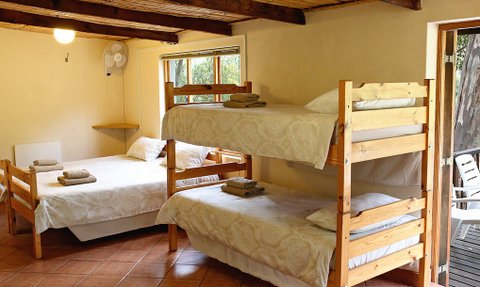 Ein gemütlicher Raum mit zwei Etagenbetten und einem Einzelbett, dekoriert mit weißen Bettwäsche und Handtüchern.