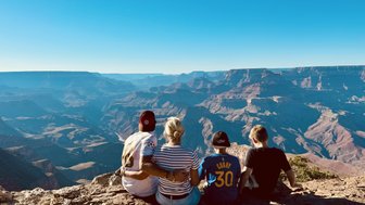 Eine Gruppe von vier Personen sitzt am Rand des Grand Canyon und genießt die atemberaubende Aussicht auf die Landschaft.