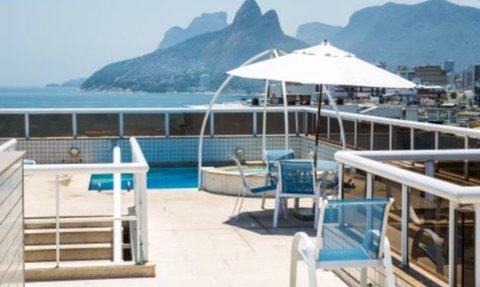 Auf der Terrasse des Atlantis Copacabana Hotels steht ein kleiner Pool mit Blick auf die Küste und die umliegenden Berge.