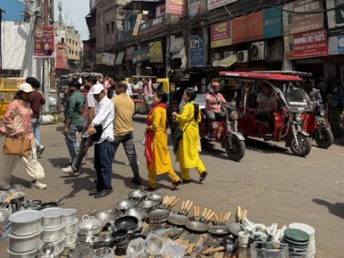 Eine belebte Marktstraße in Alt-Delhi, mit Menschen, die zwischen Ständen und Geschäften umhergehen.