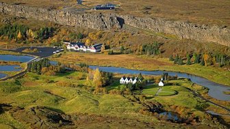 Eine malerische Landschaft mit sanften Hügeln, einem klaren Fluss und bunten Bäumen im Herbst, die die Umgebung schmücken.