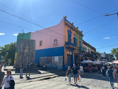 Bunte Gebäude in Buenos Aires, umgeben von Menschen, die die lebhafte Atmosphäre des Stadtteils genießen.