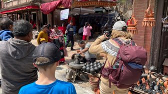 Eine Gruppe von Menschen beobachtet einen Töpfer, der kunstvolle Töpfe in einer belebten Straße in Bhaktapur formt.