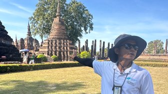 Lokaler Guide zeigt auf den Wat Mahathat Tempel in Sukhothai - Thailand Familienreise