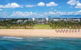 Ein atemberaubender Blick auf den Hoi An Strand mit einem luxuriösen Resort im Hintergrund und Palmen, die sanft im Wind wiegen.