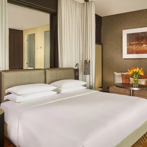 Ein elegantes Hotelzimmer mit einem großen Bett, stilvollen Möbeln und einer gemütlichen Sitzecke mit Blumenarrangement.