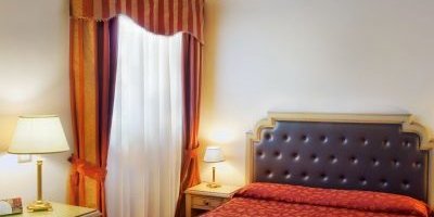 Ein elegantes Hotelzimmer mit einem großen, gepolsterten Bett und einem kunstvoll verzierten Deckenmuster.