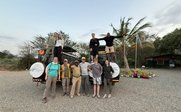 Eine Gruppe von Reisenden posiert fröhlich auf einem Geländewagen, umgeben von einer malerischen Landschaft.