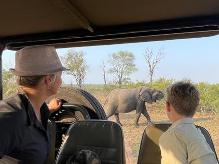 Mutter und Sohn sitzen im Safari-Jeep und beobachten gemeinsam Tiere in der Savanne – Südafrika Familienreise