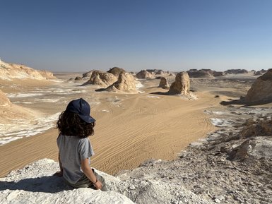 Kind sitzt auf der Weißen Wüste und genießt den Ausblick - Ägypten Reise mit Kindern