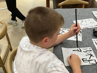 Kind schreibt chinesische Schriftzeichen bei einem Kalligrafie-Workshop – China Reise mit Kindern