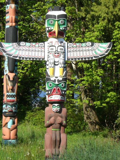 Im Stanley Park stehen mehrere farbenfrohe Totempfähle, die traditionelle indigene Kunst darstellen und die Natur umgeben.