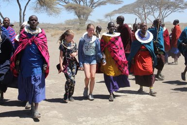 Kinder aus der Reisegruppe begleiten eine Massai-Familie beim Spaziergang – Tansania Reise mit Kindern