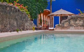 Ein ruhiger Poolbereich mit klarem Wasser, umgeben von üppigem Grün und bunten Blumen, ideal zum Entspannen.