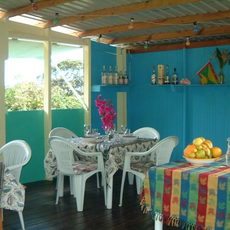 Ein einladender Essbereich mit bunten Tischen, weißen Stühlen und frischen Blumen in einer hellen, freundlichen Umgebung.