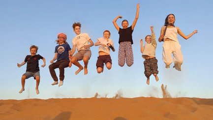 Kinder springen gemeinsam für ein Foto in der Wahiba-Wüste – Oman Reise mit Kindern